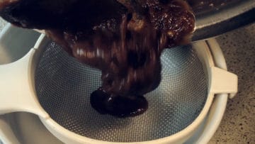 Tamarind pulp poured into strainer. | secretsofcooking.com