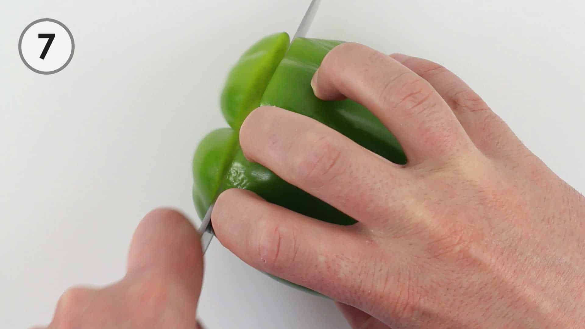 Slicing though the bottom of a bell pepper.